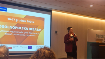Prelegent stoi z mikrofonem przed ekranem wyświetlającym slajd dotyczący krajowej debaty na temat uczenia się przez całe życie w Polsce w dniach 16-17 grudnia 2024 roku. W sali znajdują się siedzący uczestnicy i baner Fundacji Rozwoju Systemu Edukacji.