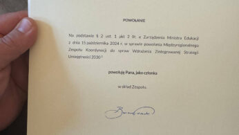 Ręka trzyma oficjalny polski dokument z logo i podpisem Ministra Edukacji. Pismo, zaadresowane do Bartłomieja Piechaczka, powiadamia go o powołaniu do zespołu koordynującego strategię edukacyjną. Dokument datowany jest na 28 października 2024 roku.
