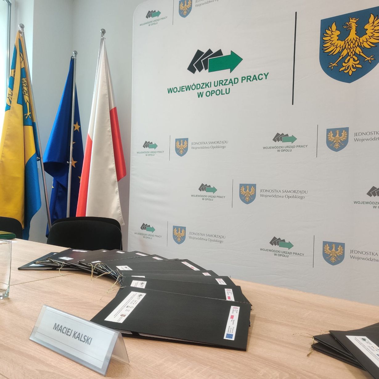Stół konferencyjny z teczkami i tabliczką z napisem 