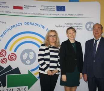 Trzy dorosłe osoby, dwie kobiety i jeden mężczyzna, stoją uśmiechnięte w strojach biznesowych przed wyświetlaczem z polskim tekstem, symbolami i logo programów edukacyjnych i unijnych. Tło zawiera niebieskie strzałki, obrazy sieci i oficjalne logo.