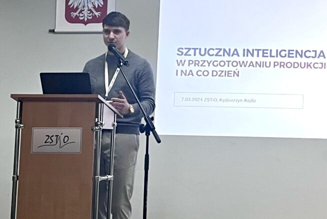 Osoba stoi na podium i wygłasza prezentację. Na ścianie powyżej wisi godło Polski z białym orłem. Na ekranie widnieje napis "Sztuczna inteligencja w przygotowaniu produkcji i na co dzień" z logo ETP Elektro. Wygląda na to, że jest w ZSTiO, z datą 7.03.2024.
