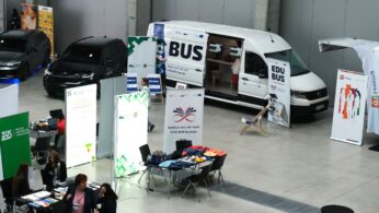 Ogólny widok hali Centrum Wystawienniczo Kongresowego w Opolu z różnymi stoiskami, w tym dużym białym vanem 