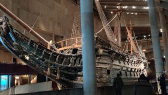 Szerokie ujęcie wraku starego statku wykonanego z drewna, umieszczonego w przestronnej Sali muzeum.