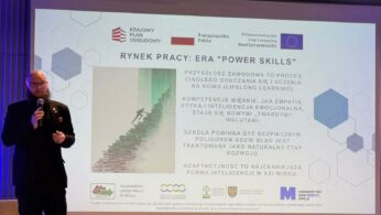 Prelegent z brodą i w okularach stoi przy dużym ekranie, na którym widnieje napis „RYNEK PRACY: ERA 'POWER SKILLS'”. Slajd zawiera tekst dotyczący kompetencji miękkich i uczenia się przez całe życie (lifelong learning). Na dole ekranu widoczne są logotypy instytucji unijnych i regionalnych.