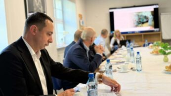 Mężczyzna przy stole notuje lub przegląda dokumenty podczas spotkania.