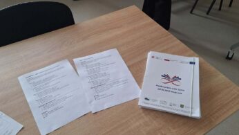 Zbliżenie na dokumenty szkoleniowe leżące na drewnianym stole, w tym stos broszur z logo „Nauka przez całe życie”. Na kartkach widoczne są nagłówki dotyczące ról pracodawcy i instytucji szkoleniowej w systemie rozwoju umiejętności. Materiały są opatrzone logotypami Funduszy Europejskich oraz Rzeczpospolitej Polskiej.