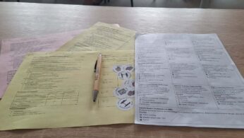 Widok z góry na dokumenty warsztatowe, w tym kolorowe karty działań oraz schematy powiązań między różnymi instytucjami. Na środku leży długopis, a arkusze zawierają tabele i opisy dotyczące rozwoju kompetencji oraz współpracy regionalnej. Tekst na kartach jest w języku polskim i dotyczy m.in. Agencji Rozwoju Regionalnego.