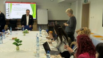 Prowadzący prezentuje materiał przy ekranie, uczestnicy słuchają.