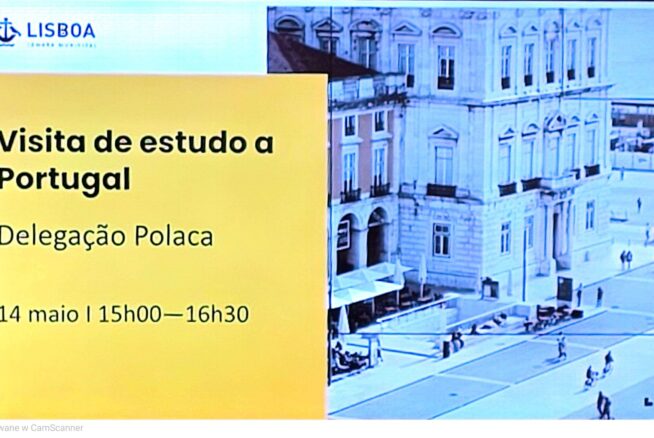 Zdjęcie przedstawia slajd z prezentacji wyświetlanej na ekranie z logo „LISBOA” w lewym górnym rogu. Na żółtym tle widnieje czarny napis w języku portugalskim „Visita de estudo a Portugal Delegação Polaca” oraz data i godzina. Po prawej stronie tekstu umieszczono czarno-białą grafikę przedstawiającą plac miejski.