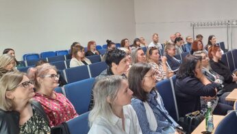 Uczestnicy spotkania siedzący w sali wykładowej podczas wydarzenia, słuchający prelegenta
