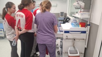 Grupa osób podczas zajęć lub szkolenia w pracowni medycznej przy specjalistycznym sprzęcie