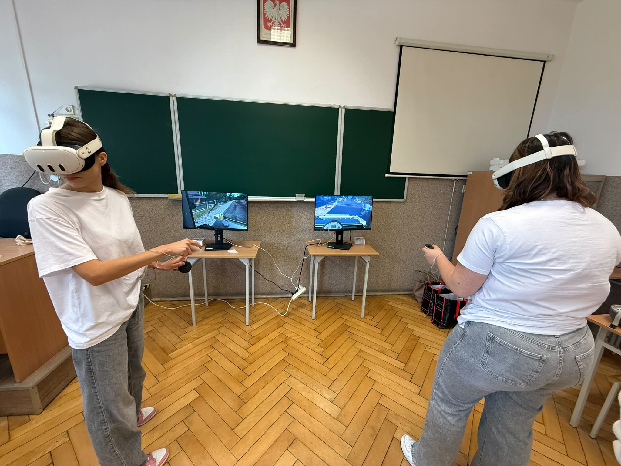 Dwie osoby podczas zajęć z wykorzystaniem gogli VR wykonują ćwiczenia przy stanowiskach komputerowych.