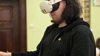 Osoba w goglach VR trzyma kontrolery i wykonuje ćwiczenia w wirtualnym środowisku.