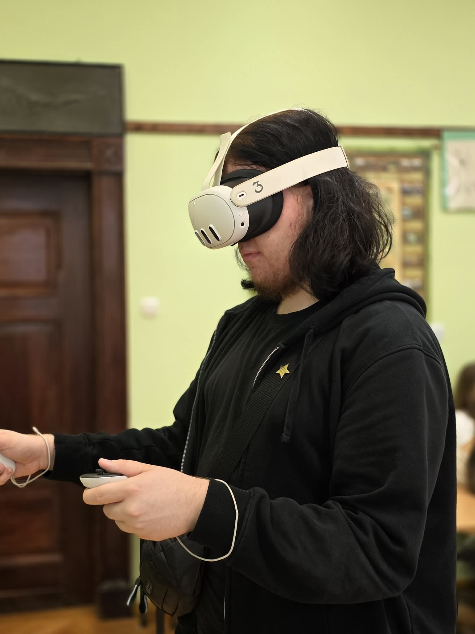 Osoba w goglach VR trzyma kontrolery i wykonuje ćwiczenia w wirtualnym środowisku.