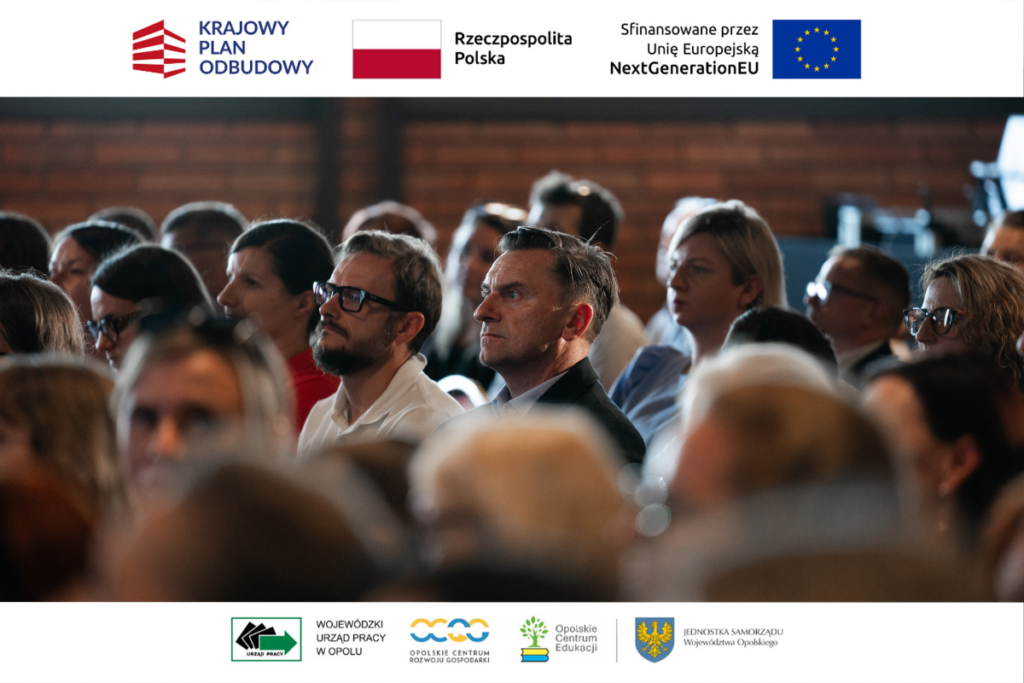 Zbliżenie na twarze uczestników konferencji siedzących na widowni. W centrum uwagi znajduje się profil mężczyzny w ciemnej marynarce, a obok niego siedzi inny mężczyzna w okularach i z brodą. W tle widać zarysy innych osób oraz fragment ceglanej ściany. Górny i dolny margines zdjęcia zawiera logotypy organizatorów i programów finansujących, w tym Krajowego Planu Odbudowy.