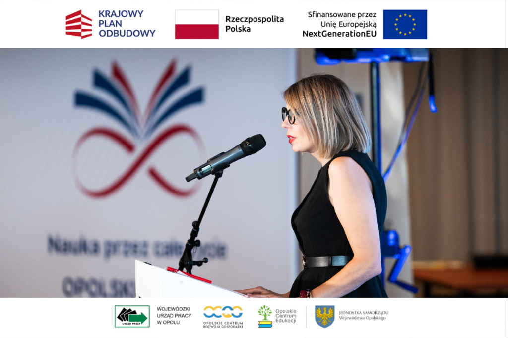 Kobieta w okularach i czarnej sukience bez rękawów stoi z profilu za białą mównicą i przemawia do mikrofonu. W tle widoczna jest rozmyta grafika ścienna przedstawiająca logotyp z motywem otwartej książki i znaku nieskończoności. Całość zdjęcia ujęta jest w charakterystyczne białe ramki z logotypami m.in. Wojewódzkiego Urzędu Pracy w Opolu oraz Opolskiego Centrum Edukacji.